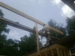 Carpenter setting a ridge beam over a new addition frame — Ice Dam Removal by Roofing Brothers in Homeland