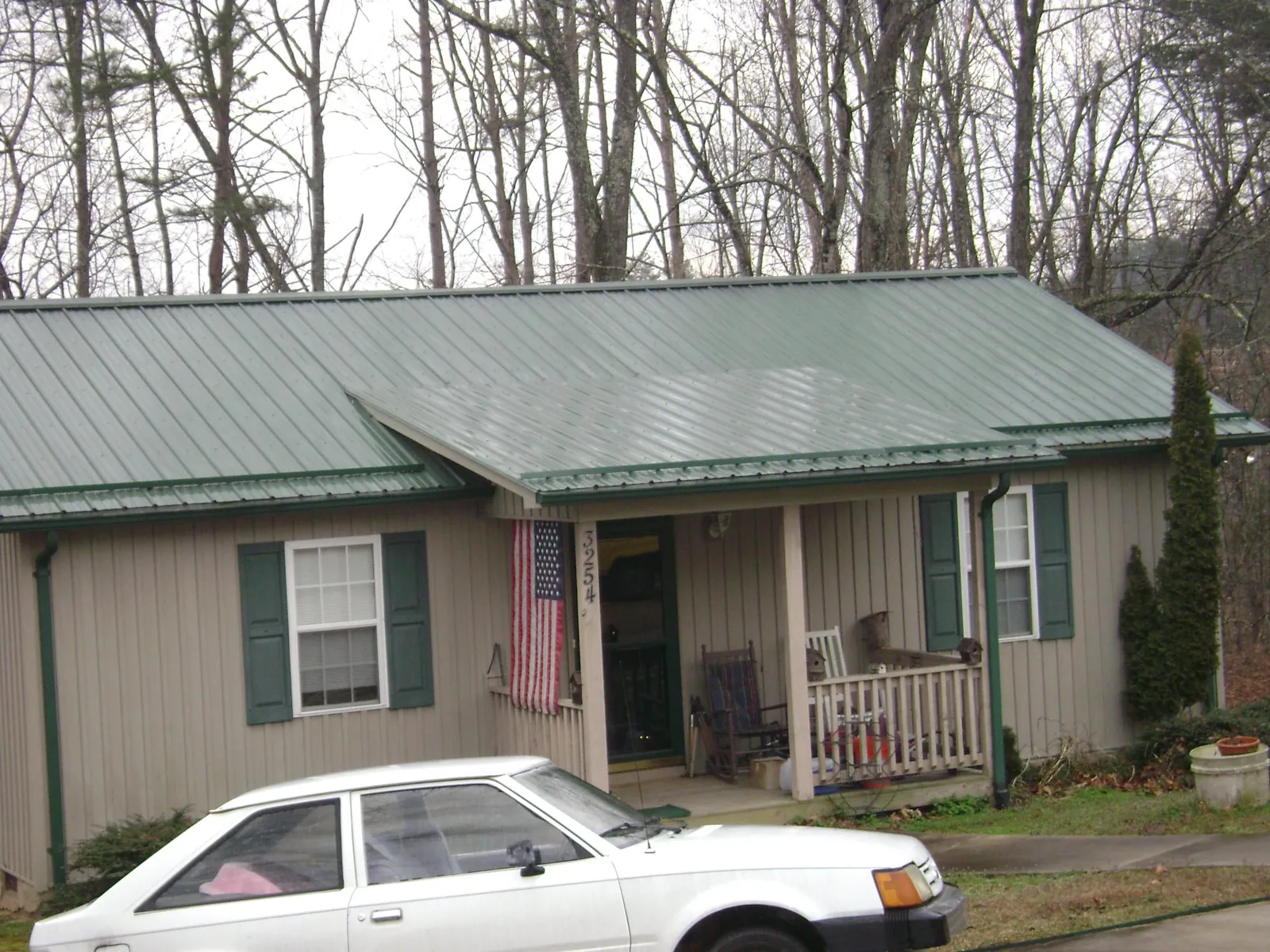 Green metal roof and front porch on a tan sided cottage in Homeland